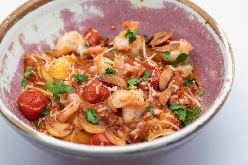 Shrimp basket with tomato sauce, cherry tomatoes, garlic, parsley, and cheese.