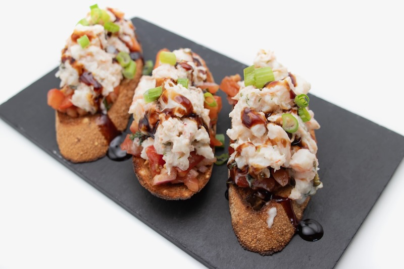 Three slices of bruschetta with various toppings.