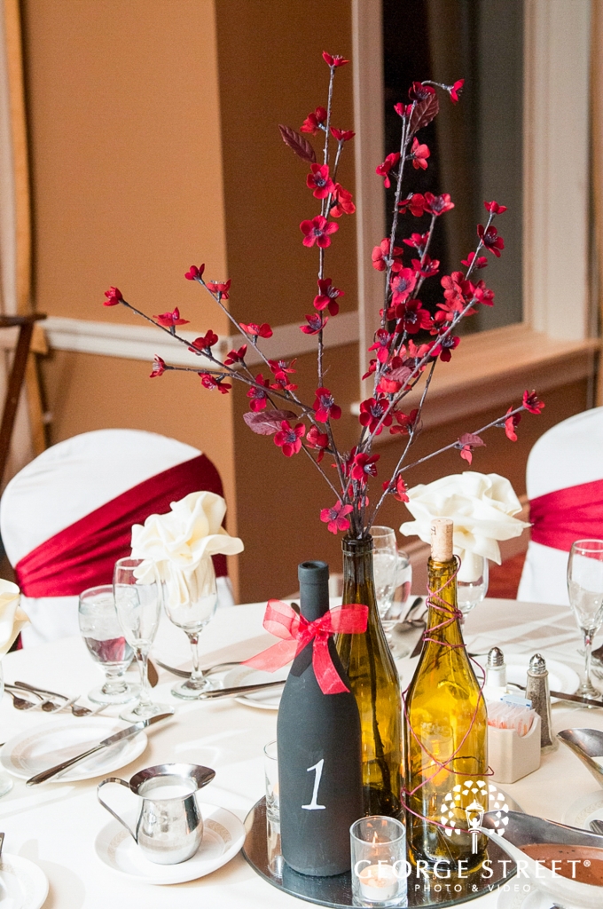 painted wine bottles with red flowers and white reception table decor_680_1024
