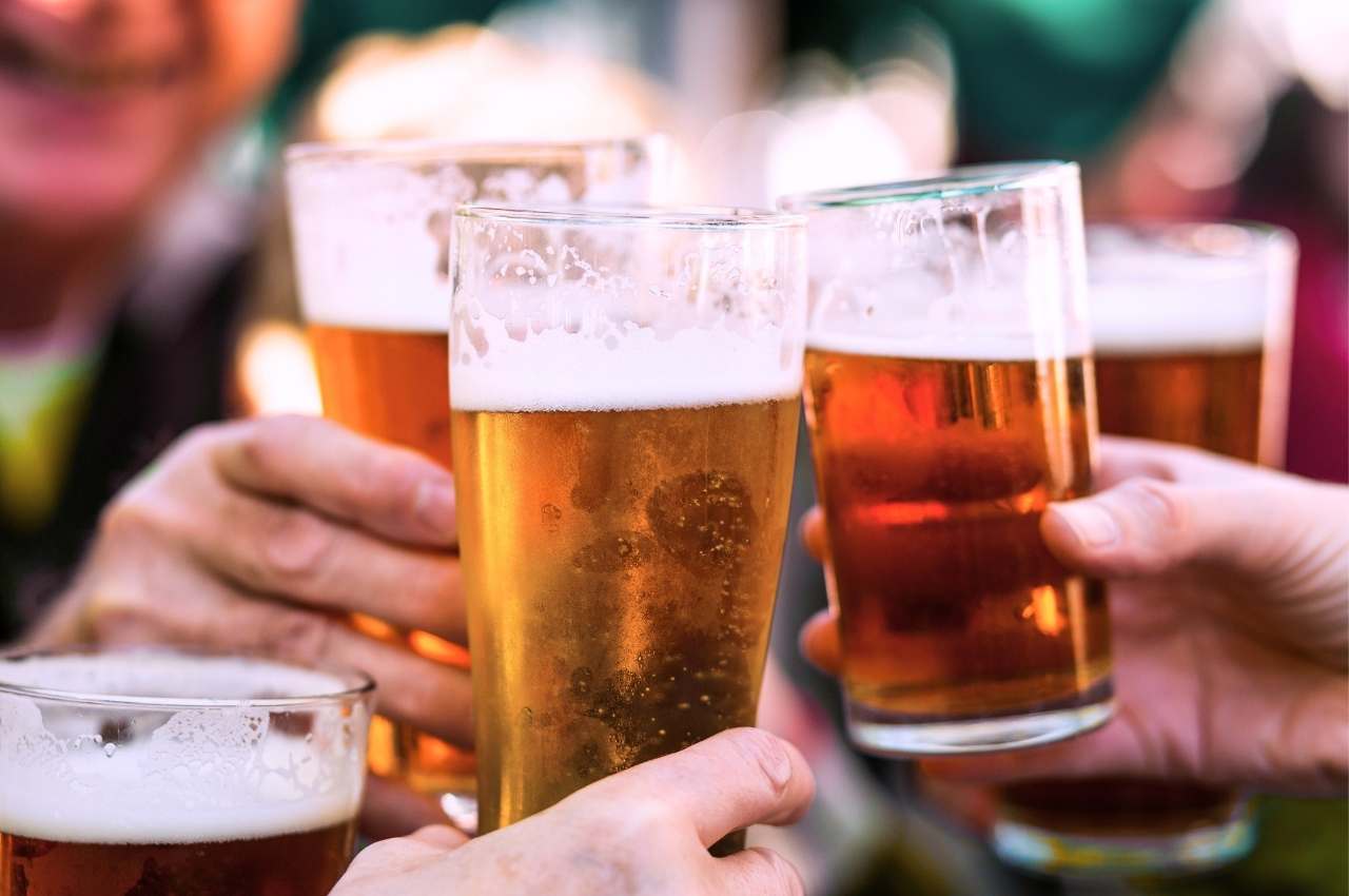 People clinking pint glasses of draft beer